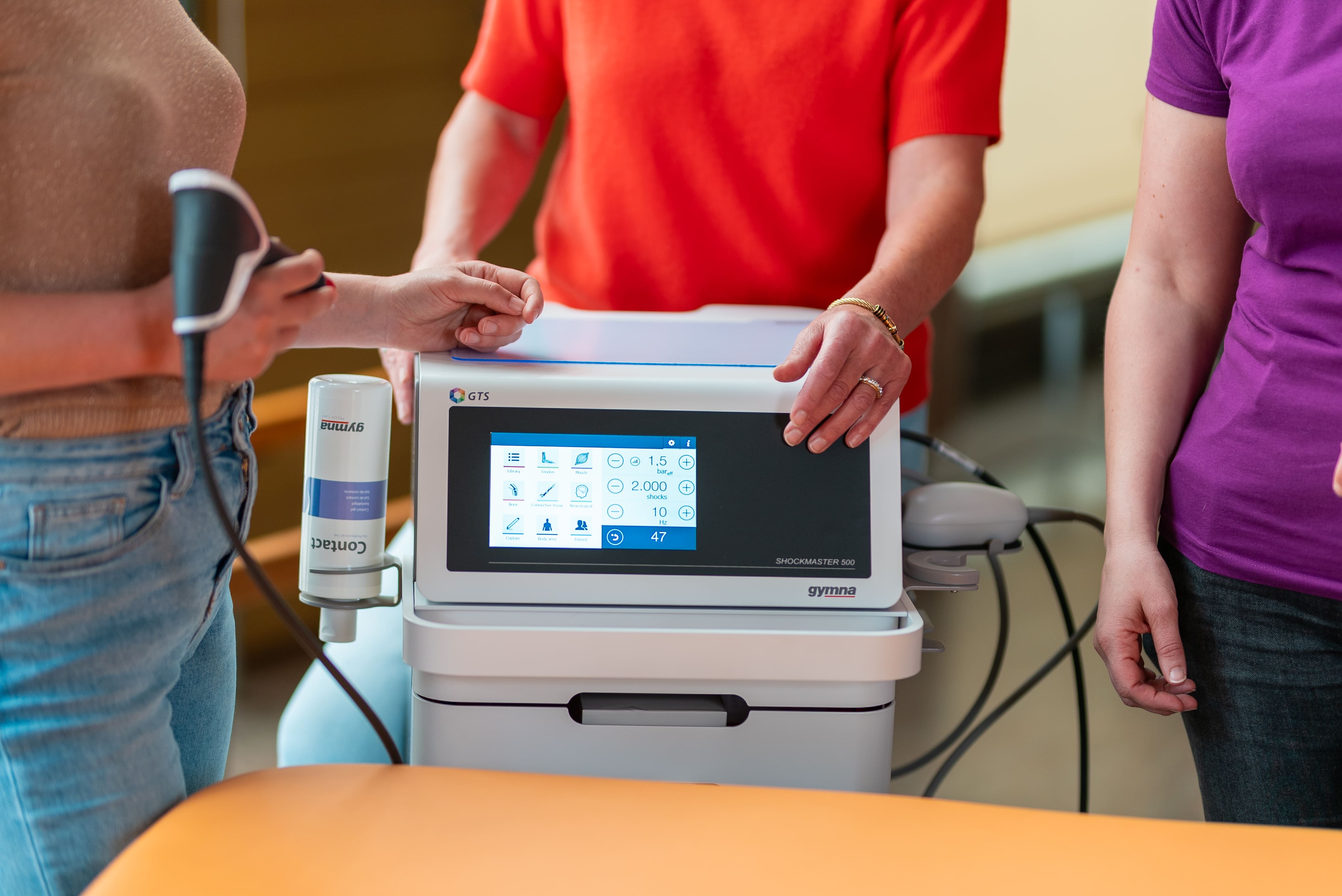 Physiotherapists standing around the shockwave device used for treating paediatric spasticity